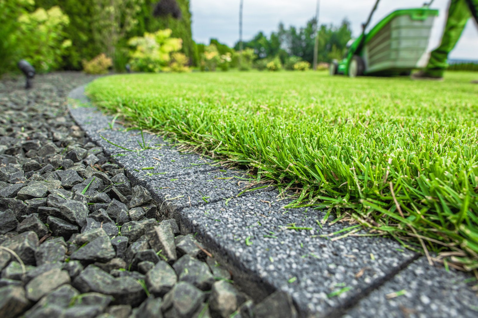 Backyard Lawn Grass Field Cobble Edge. Grass Mowing and Edges Finishing. Gardening and Landscaping Industry Theme.